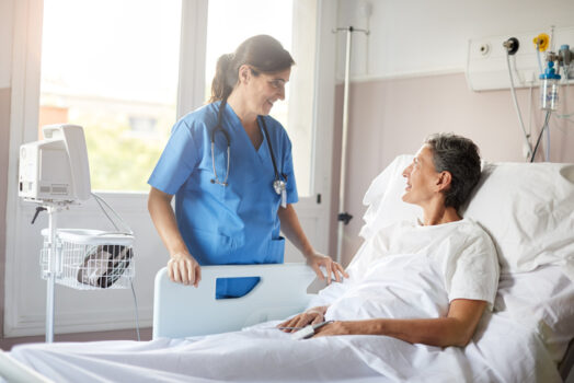 A caucassian nurse talking to a patient lying down on bed.